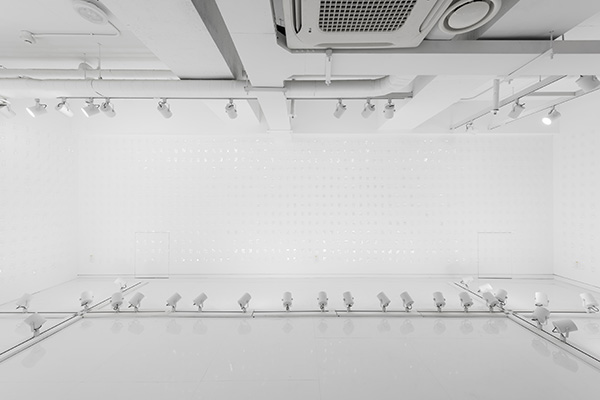 White gallery installation with transparent wall-mounted elements and floor lights